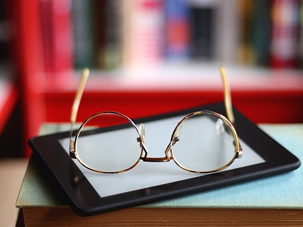 Kindle and reading glasses on top of a book